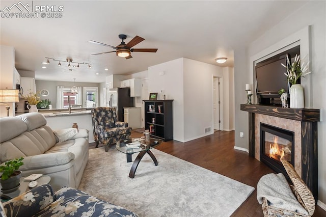 7833 Bengali Ln, Colorado Springs, CO 80923 - living area featuring dark wood-type flooring, a ceiling fan, a tiled fireplace, and baseboards