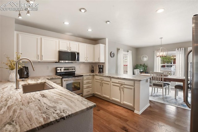 7833 Bengali Ln, Colorado Springs, CO 80923 - kitchen with appliances with stainless steel finishes, a sink, a peninsula, light stone counters, and wood finished floors