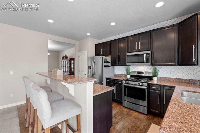 7856 Calabash Rd, Colorado Springs, CO 80908 - kitchen featuring stainless steel appliances, a breakfast bar, light stone countertops, decorative backsplash, and recessed lighting
