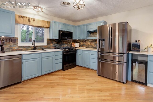 417 W Columbine Ave, Woodland Park, CO 80863 - kitchen featuring appliances with stainless steel finishes, a sink, blue cabinetry, beverage cooler, and light countertops