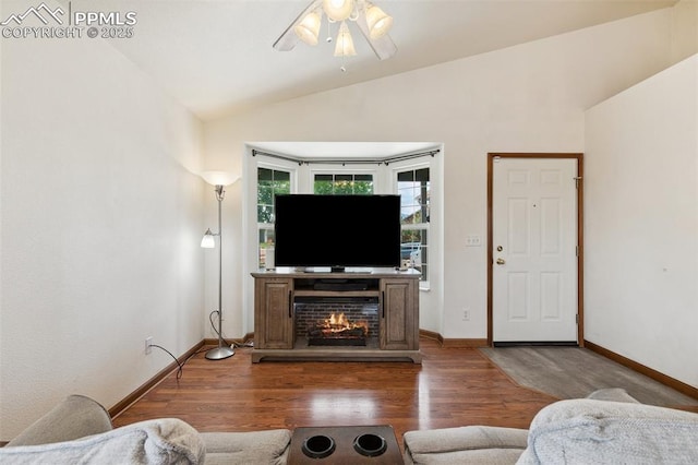 5630 Almont Ave, Colorado Springs, CO 80911 - living area featuring vaulted ceiling, a ceiling fan, wood finished floors, baseboards, and a warm lit fireplace