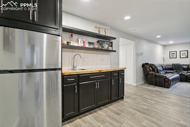 12912 Fishers Island Rd, Peyton, CO 80831 - kitchen with freestanding refrigerator, butcher block counters, a sink, open floor plan, and dark cabinetry