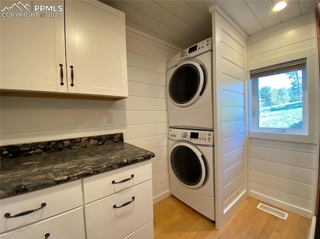 845 Markus Rd, Woodland Park, CO 80863 - laundry area with estacked washer and dryer, light wood finished floors, cabinet space, and wood walls