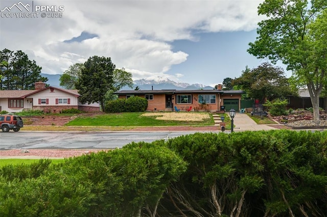 751 Crown Ridge Dr, Colorado Springs, CO 80904 - single story home with a front yard, a mountain view, and a chimney