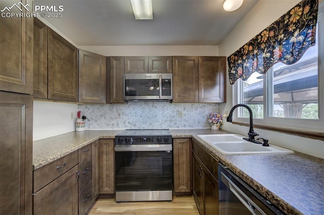 6938 Big Timber Dr, Colorado Springs, CO 80923 - kitchen with stainless steel appliances, a sink, light wood-style floors, and backsplash