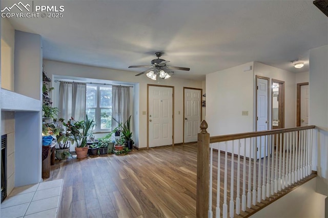 6938 Big Timber Dr, Colorado Springs, CO 80923 - foyer with light wood-type flooring, a ceiling fan, a tile fireplace, and baseboards