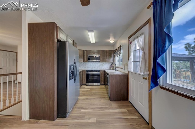 6938 Big Timber Dr, Colorado Springs, CO 80923 - kitchen featuring stainless steel appliances, light wood-style floors, a sink, light countertops, and decorative backsplash