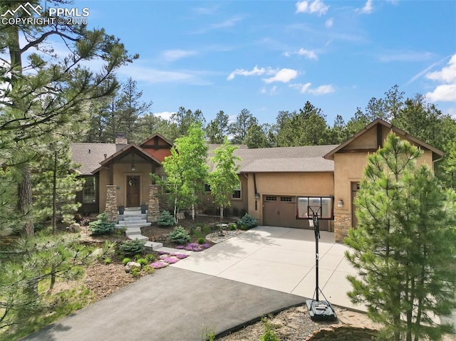 11720 Smokey Hill Grv, Colorado Springs, CO 80908 - view of front facade featuring stucco siding, an attached garage, stone siding, driveway, and a chimney