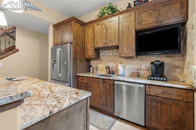 11720 Smokey Hill Grv, Colorado Springs, CO 80908 - kitchen with appliances with stainless steel finishes, decorative backsplash, light stone countertops, and brown cabinets