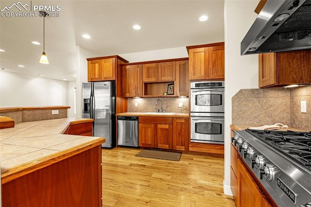 4775 Neeper Valley Rd, Manitou Springs, CO 80829 - kitchen with wall chimney exhaust hood, appliances with stainless steel finishes, a sink, brown cabinets, and open shelves
