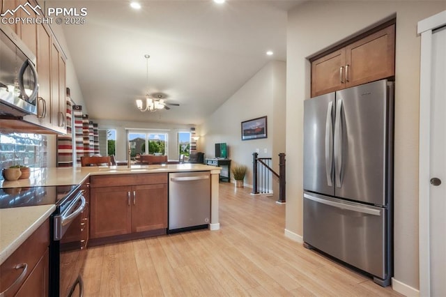 6015 Trappers Tale Ct, Colorado Springs, CO 80923 - kitchen featuring stainless steel appliances, a peninsula, vaulted ceiling, a chandelier, and light wood-type flooring