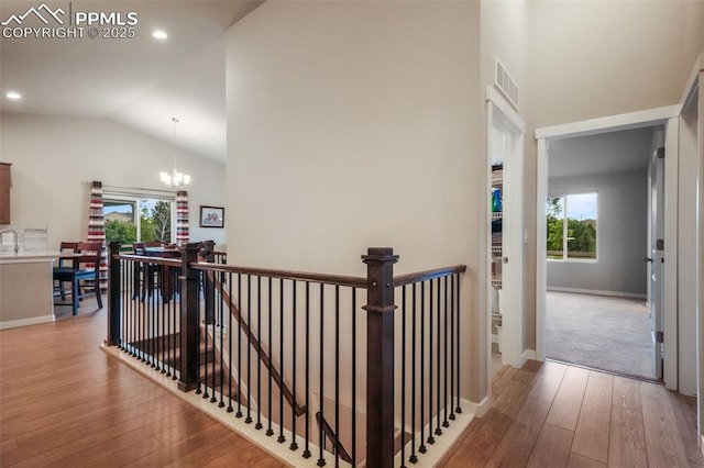6015 Trappers Tale Ct, Colorado Springs, CO 80923 - corridor featuring an upstairs landing, wood-type flooring, plenty of natural light, vaulted ceiling, and a chandelier