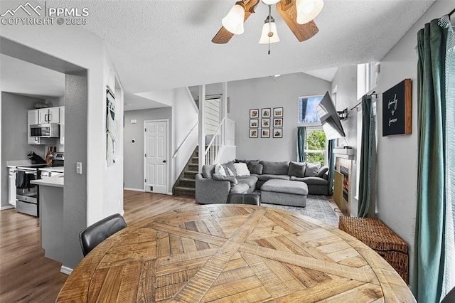 2280 Lisa Dr, Colorado Springs, CO 80915 - dining area featuring stairs, ceiling fan, light wood-style flooring, a lit fireplace, and baseboards
