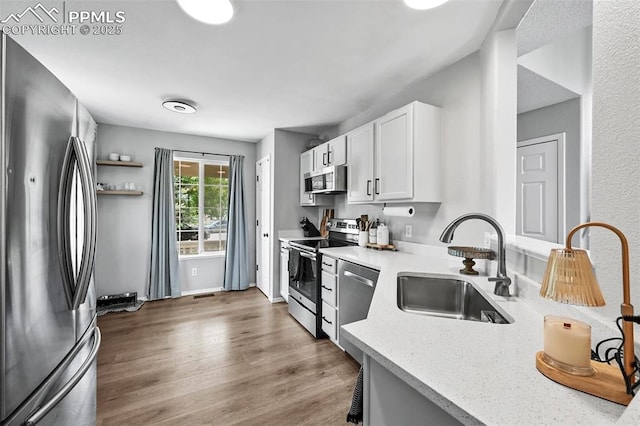 2280 Lisa Dr, Colorado Springs, CO 80915 - kitchen featuring stainless steel appliances, a sink, light countertops, white cabinetry, and wood finished floors