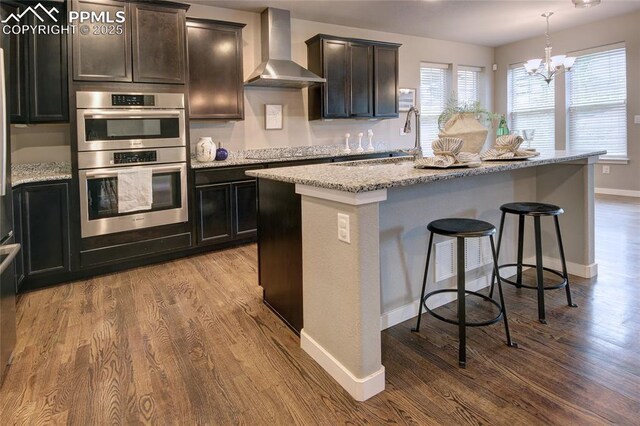 4228 Notch Trl, Colorado Springs, CO 80924 - kitchen featuring wall chimney exhaust hood, stainless steel double oven, a sink, wood finished floors, and light stone countertops