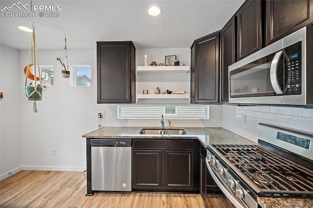 5840 Thurless Ln, Colorado Springs, CO 80927 - kitchen with stainless steel appliances, a sink, light wood-style flooring, tasteful backsplash, and baseboards