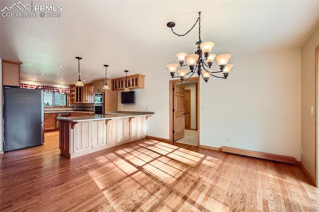 14820 Spiritwood Loop, Elbert, CO 80106 - kitchen featuring appliances with stainless steel finishes, glass insert cabinets, a peninsula, a chandelier, and light wood-style flooring