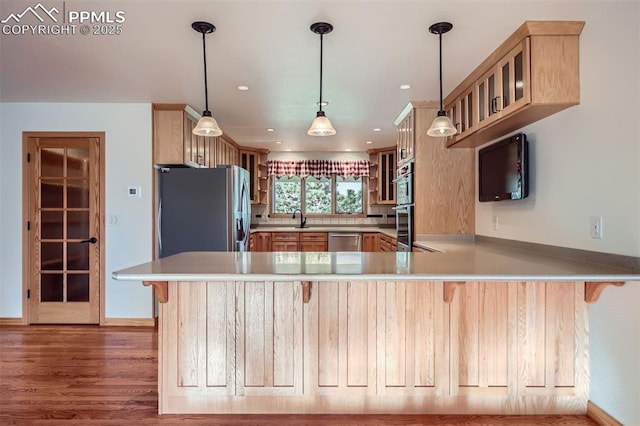 14820 Spiritwood Loop, Elbert, CO 80106 - kitchen featuring appliances with stainless steel finishes, a peninsula, light brown cabinets, light countertops, and glass insert cabinets