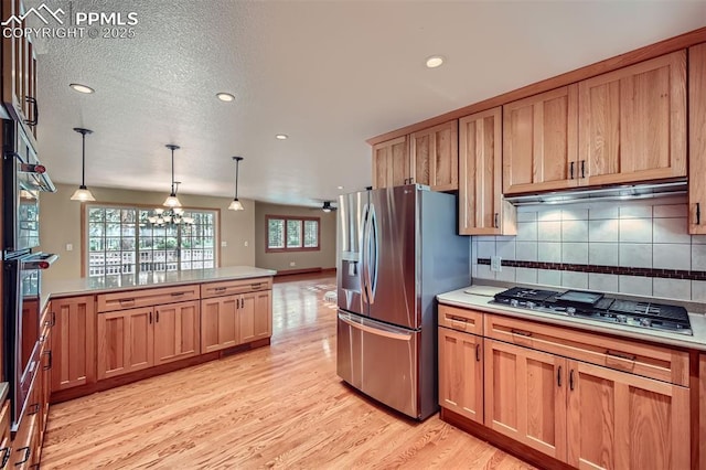 14820 Spiritwood Loop, Elbert, CO 80106 - kitchen with stainless steel appliances, light wood finished floors, decorative backsplash, a chandelier, and pendant lighting