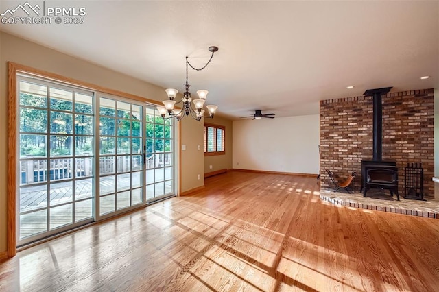 14820 Spiritwood Loop, Elbert, CO 80106 - unfurnished living room with a chandelier, ceiling fan, wood finished floors, and a wood stove