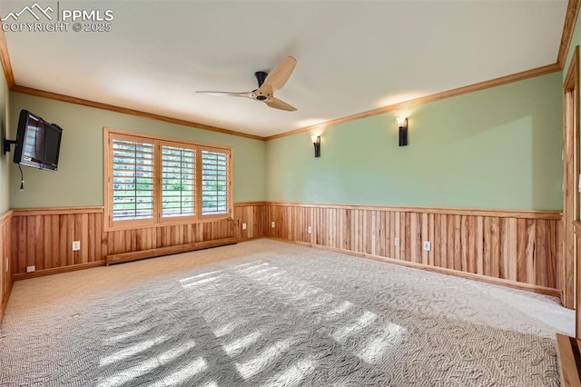 14820 Spiritwood Loop, Elbert, CO 80106 - empty room featuring a wainscoted wall, ceiling fan, ornamental molding, carpet, and wood walls