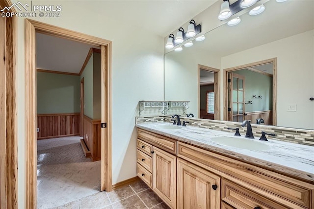 14820 Spiritwood Loop, Elbert, CO 80106 - bathroom with double vanity, a wainscoted wall, backsplash, and tile patterned floors