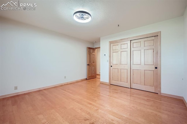 14820 Spiritwood Loop, Elbert, CO 80106 - unfurnished bedroom with light wood-type flooring, a closet, and a textured ceiling