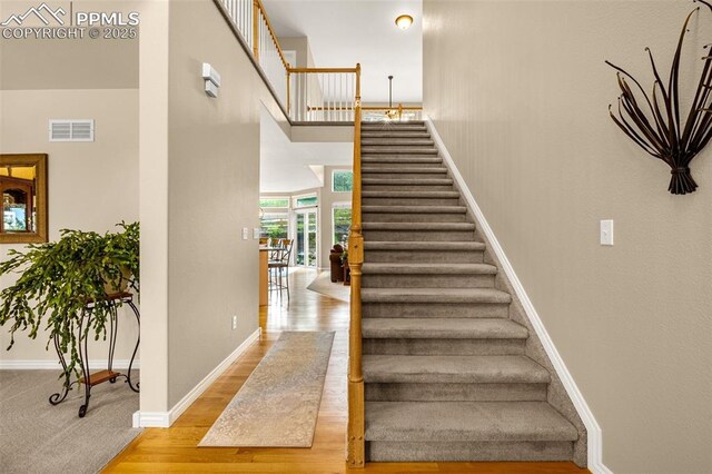 12265 Jones Park Ct, Colorado Springs, CO 80921 - staircase featuring baseboards, wood finished floors, and a high ceiling