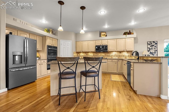 12265 Jones Park Ct, Colorado Springs, CO 80921 - kitchen featuring black appliances, a breakfast bar, decorative backsplash, light wood-style floors, and dark stone counters