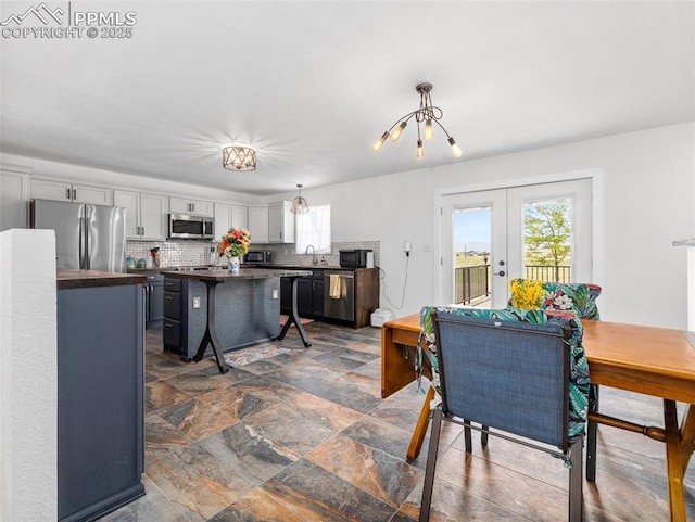 1159 N Linda Ln, Pueblo West, CO 81007 - dining space featuring healthy amount of natural light, french doors, dark stone finish floors, and a chandelier