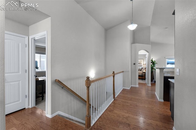 8795 Canary Cir, Colorado Springs, CO 80908 - corridor featuring an upstairs landing, wood finished floors, arched walkways, lofted ceiling, and baseboards