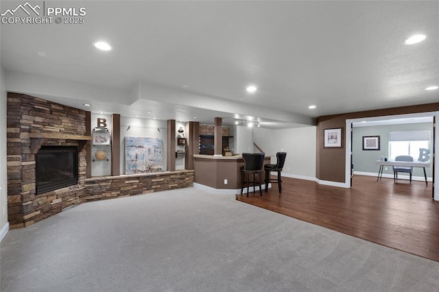 8795 Canary Cir, Colorado Springs, CO 80908 - living area featuring dark carpet, recessed lighting, bar, a stone fireplace, and baseboards