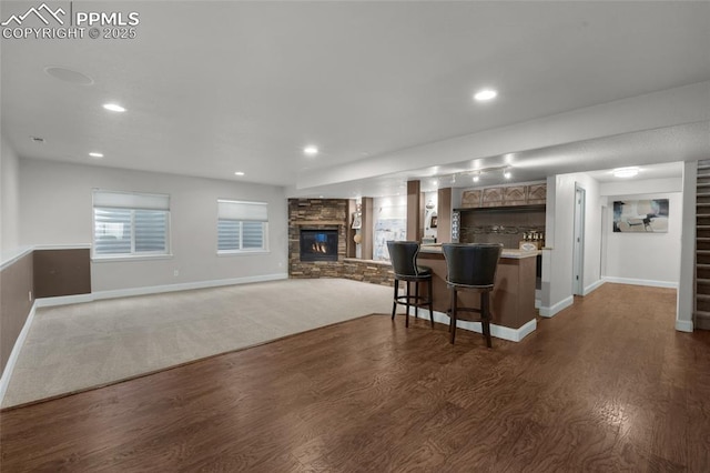 8795 Canary Cir, Colorado Springs, CO 80908 - kitchen with baseboards, dark wood-type flooring, a fireplace, a breakfast bar, and recessed lighting