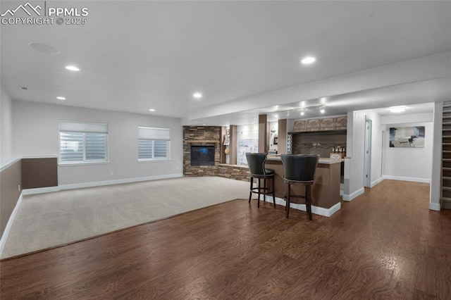 8795 Canary Cir, Colorado Springs, CO 80908 - kitchen featuring dark wood finished floors, a fireplace, baseboards, a breakfast bar area, and recessed lighting