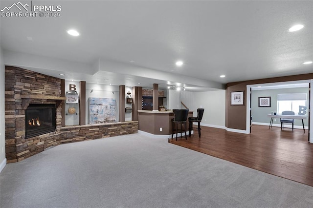 8795 Canary Cir, Colorado Springs, CO 80908 - carpeted living room featuring recessed lighting, a fireplace, baseboards, bar area, and wood finished floors