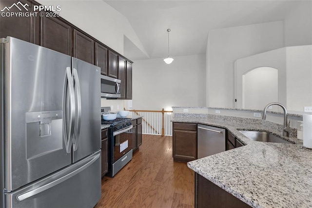 8795 Canary Cir, Colorado Springs, CO 80908 - kitchen featuring stainless steel appliances, a sink, wood finished floors, lofted ceiling, and light stone counters