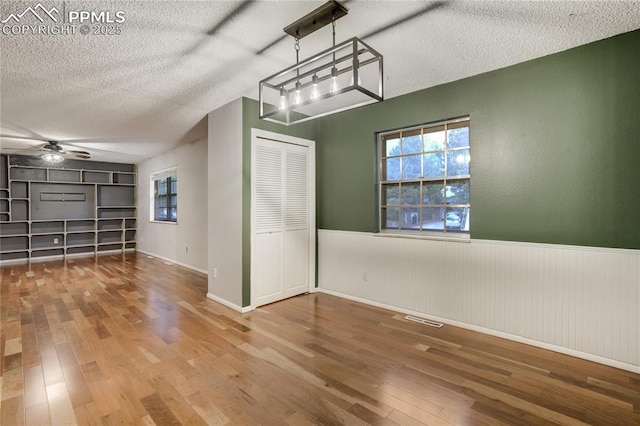 4708 Sprucewood Dr, Colorado Springs, CO 80918 - unfurnished dining area featuring hardwood / wood-style flooring, ceiling fan, wainscoting, and a textured ceiling