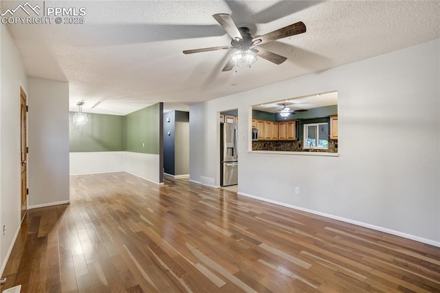 4708 Sprucewood Dr, Colorado Springs, CO 80918 - unfurnished living room with wood finished floors, a ceiling fan, baseboards, and a textured ceiling