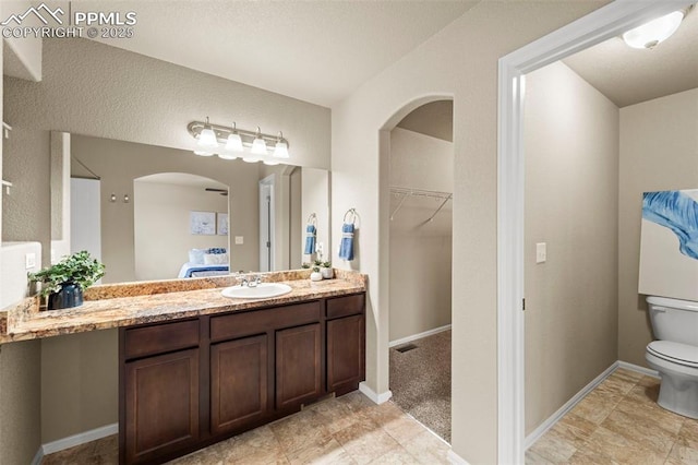 7315 Forest Meadows Ave, Colorado Springs, CO 80908 - ensuite bathroom featuring toilet, vanity, a spacious closet, and baseboards