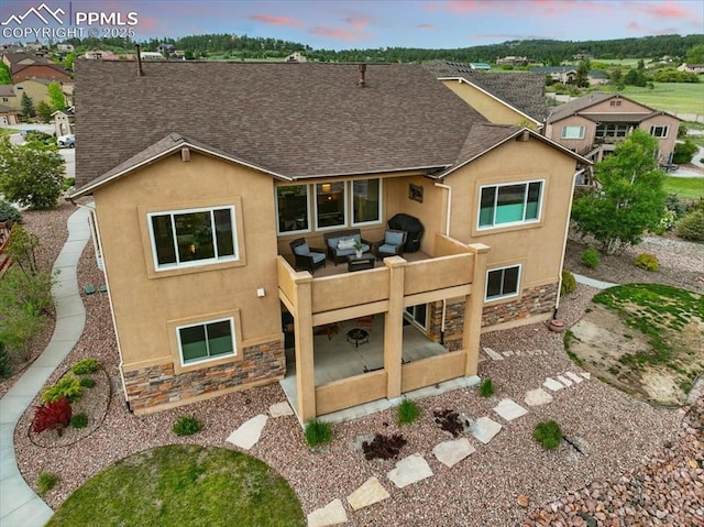 15506 Short Line Ct, Monument, CO 80132 - back of property featuring outdoor lounge area, stone siding, stucco siding, a patio area, and a shingled roof