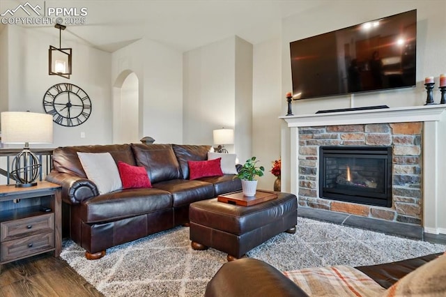 15506 Short Line Ct, Monument, CO 80132 - living room with arched walkways, a stone fireplace, and wood finished floors