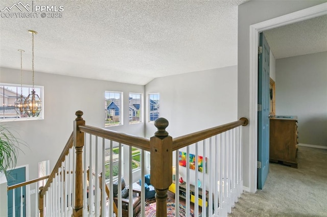 7942 French Rd, Colorado Springs, CO 80920 - hallway with a textured ceiling, an upstairs landing, a chandelier, carpet, and baseboards