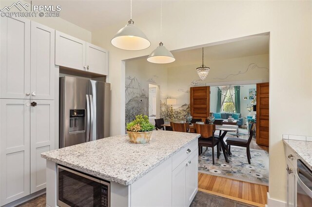 1212 W Cucharras St, Colorado Springs, CO 80904 - kitchen with appliances with stainless steel finishes, light stone countertops, a center island, hanging light fixtures, and white cabinetry