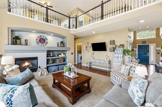 6950 Blue Mesa Ln, Littleton, CO 80125 - living area featuring a high ceiling, washer / clothes dryer, a fireplace, baseboards, and wood finished floors