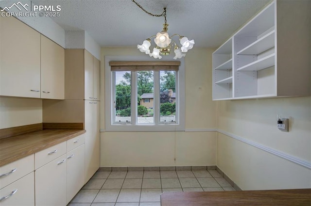 130 Cresta Rd, Colorado Springs, CO 80906 - unfurnished dining area with a chandelier, light tile patterned floors, a textured ceiling, and baseboards