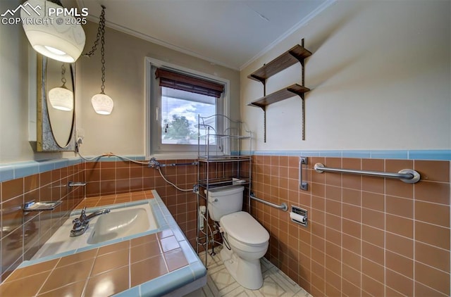 130 Cresta Rd, Colorado Springs, CO 80906 - bathroom featuring crown molding, toilet, tile walls, wainscoting, and a sink