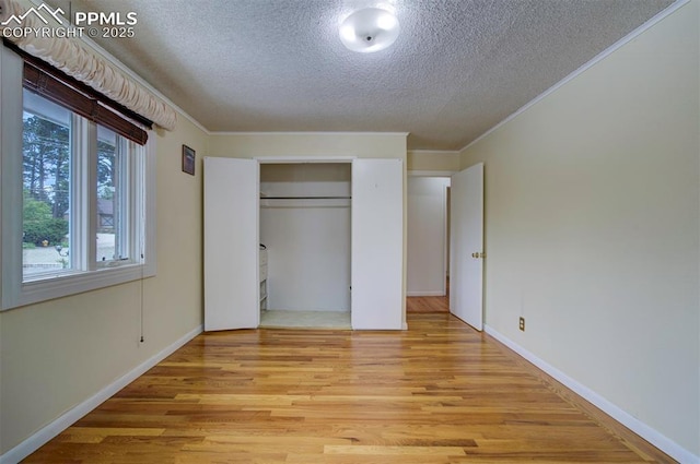 130 Cresta Rd, Colorado Springs, CO 80906 - unfurnished bedroom with a textured ceiling, light wood-style floors, ornamental molding, a closet, and baseboards