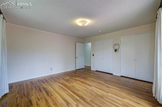 130 Cresta Rd, Colorado Springs, CO 80906 - unfurnished bedroom featuring light wood finished floors, a textured ceiling, two closets, and baseboards