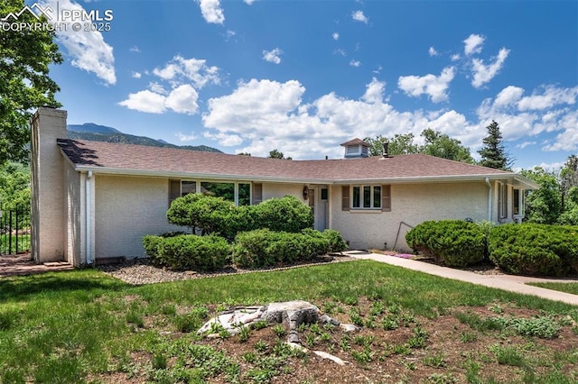 130 Cresta Rd, Colorado Springs, CO 80906 - ranch-style house with a chimney, brick siding, and a front lawn