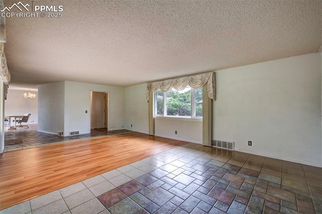 130 Cresta Rd, Colorado Springs, CO 80906 - spare room featuring a chandelier, a textured ceiling, baseboards, and wood finished floors